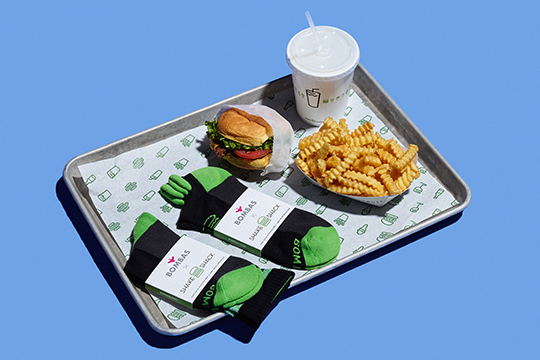 shake shack bombas socks next to a soda, burger, and fries on a tray