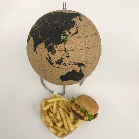Shake Shack pin on a globe with burger and fries in front of globe
