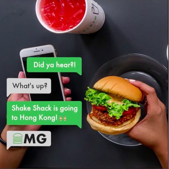 Hong Kong announcement with cell phone text messages and hand holding a shake shack burger