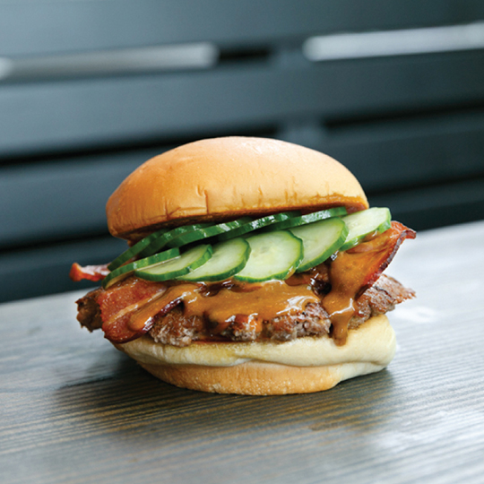 shake shack den shack all-natural 100% Angus beef burger topped with applewood-smoked bacon, DEN miso ShackSauce, sansho pepper and house-pickled cucumbers