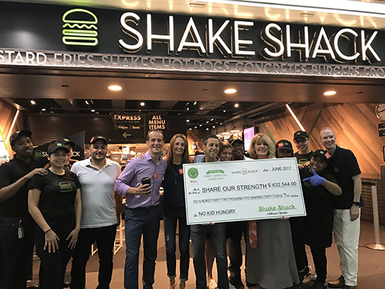 shake shack employees holding an oversized check for no kid hungry