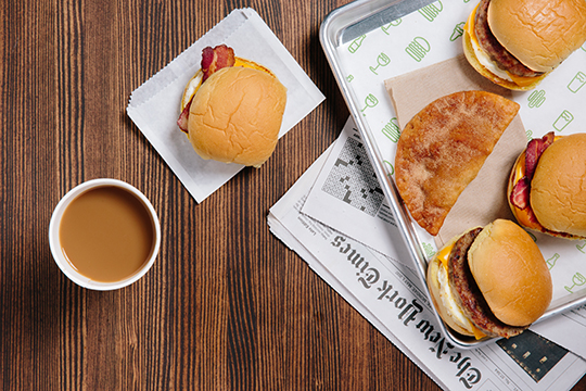 shake shack breakfast sandwiches on a tray next to a cup of coffee