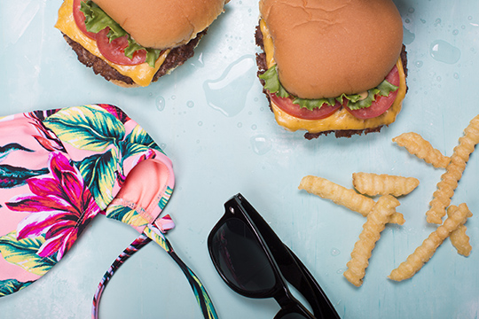 shake shack burgers with fries next to a swimsuit and sunglasses
