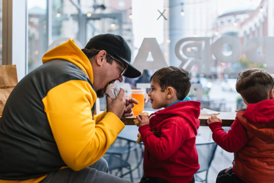 A father eating a Shake Shack burger while son watches