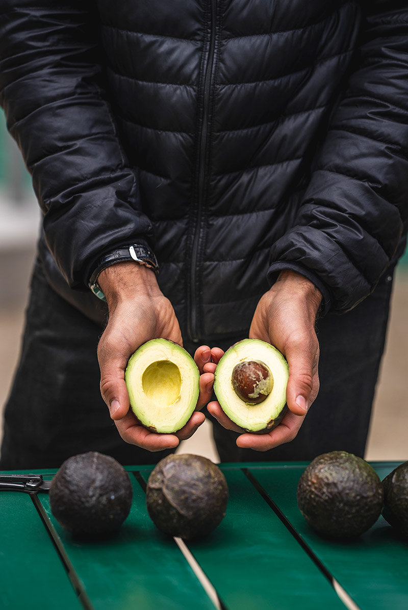 Hands holding halved avocado
