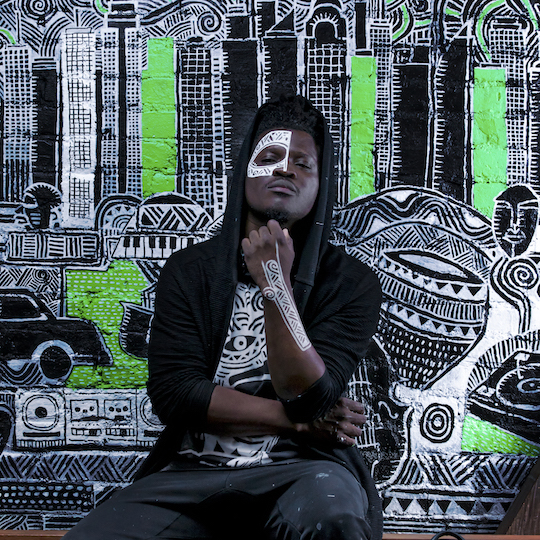 Laolu sitting in front of art and posing for a photo