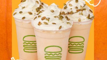 three shakes with seed toppings. The background is different shades of orange, and there are outlines of three pumpkins.