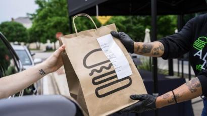 shake shack employee handing a shake shack bag to a customer