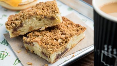 two rectangular slices of carrot cake sitting on a tray. There is a cup of coffee next to the tray.