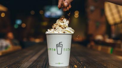 Hand sprinkling toppings on top of a shake