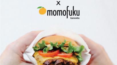 Shake Shack x Momofuku text. Two hands holding a burger below it.
