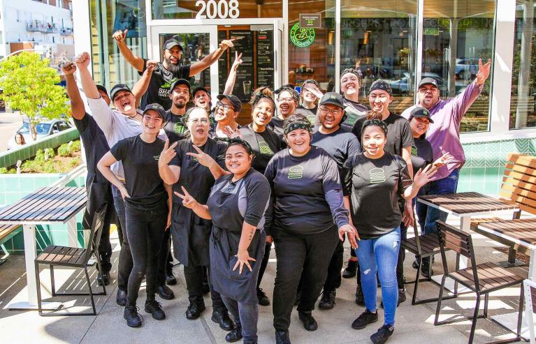 Group of Shake Shack employees standing outside looking joyful