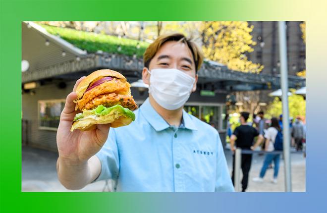 Junghyun Park holding a sandwich outside of Shake Shack