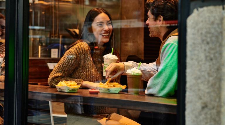 Woman and man eating shake shack in a booth